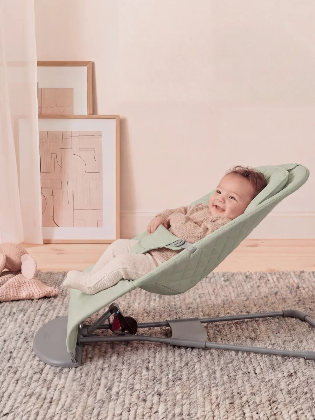 Vue de profil d'un transat pour nouveau-né incliné avec structure grise et assise matelassée verte.