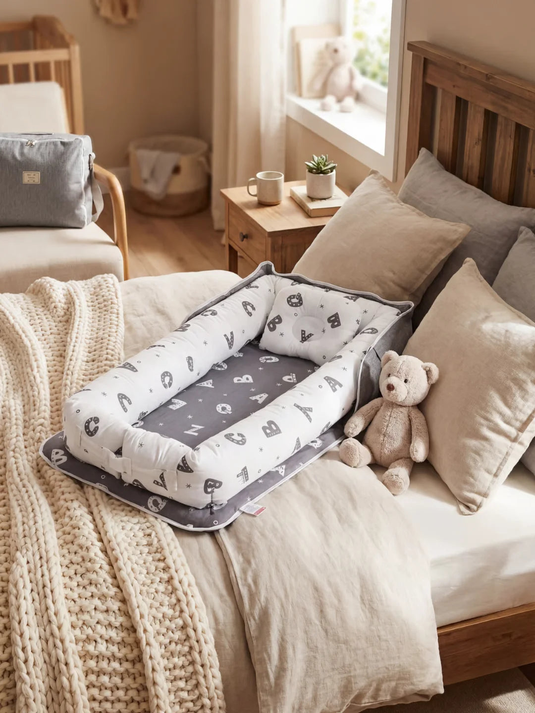 Réducteur de lit bébé gris avec motif lettres de l'alphabet posé sur un lit