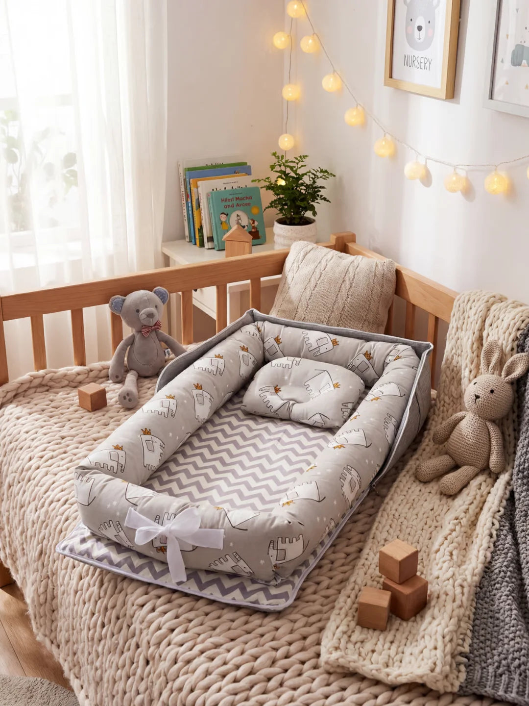 Réducteur de lit bébé gris avec motif éléphants à couronnes posé dans un lit à barreaux