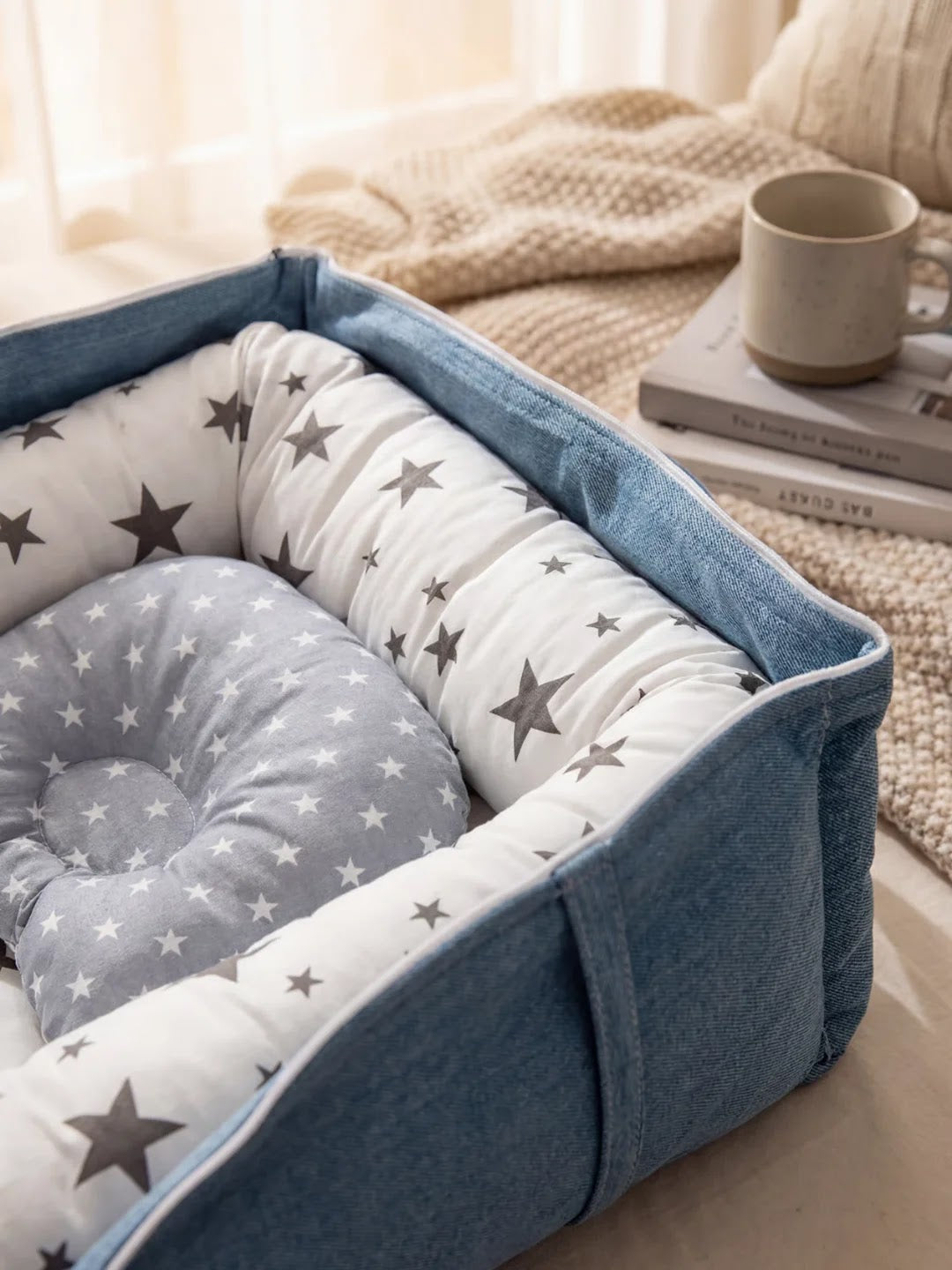Réducteur de lit bleu et gris avec motif étoiles vu de dessus, posé sur un lit avec tasse et livres.
