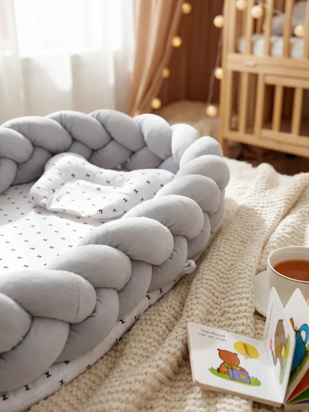Réducteur de lit tressé gris dans une chambre bébé cosy avec livres