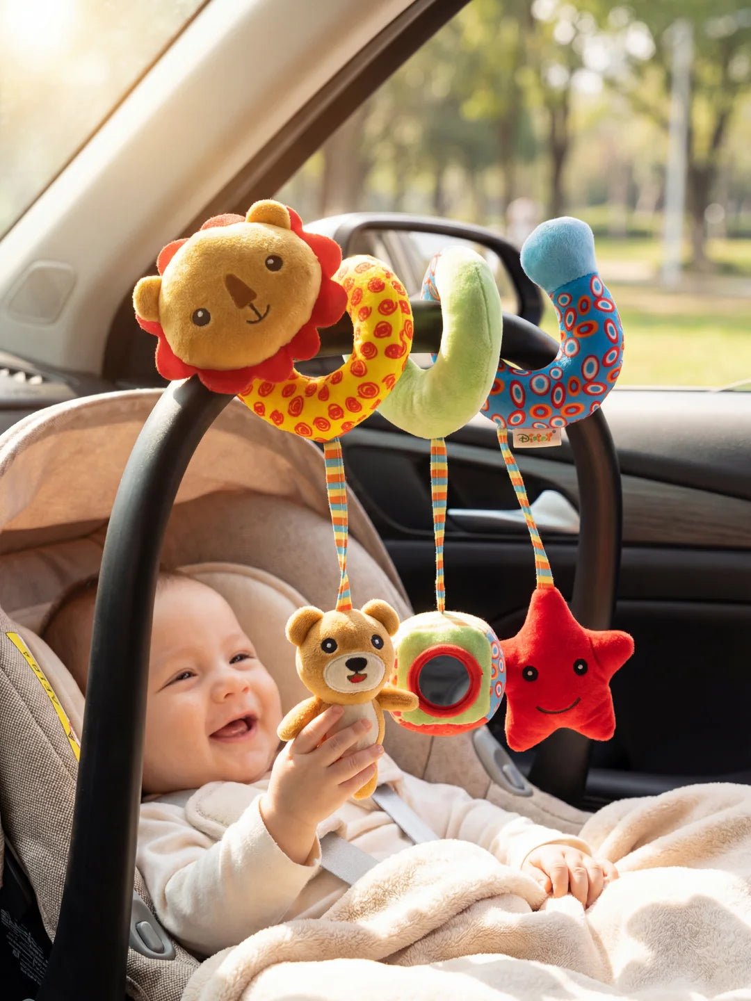 Bébé souriant dans son cosy jouant avec une spirale d'éveil lion aux couleurs vives.
