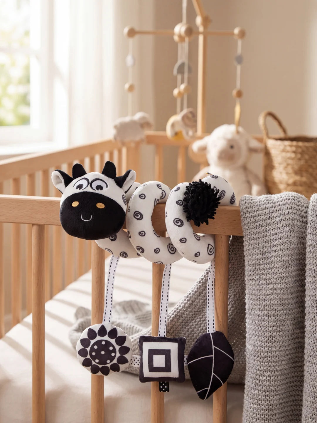 Spirale d'éveil contrastée noir et blanc avec tête de vachette fixée sur un lit à barreaux.