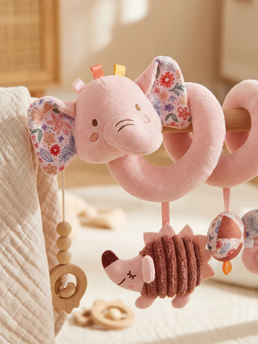 Détail de la tête de l'éléphant en peluche rose avec oreilles aux motifs fleurs printanières.
