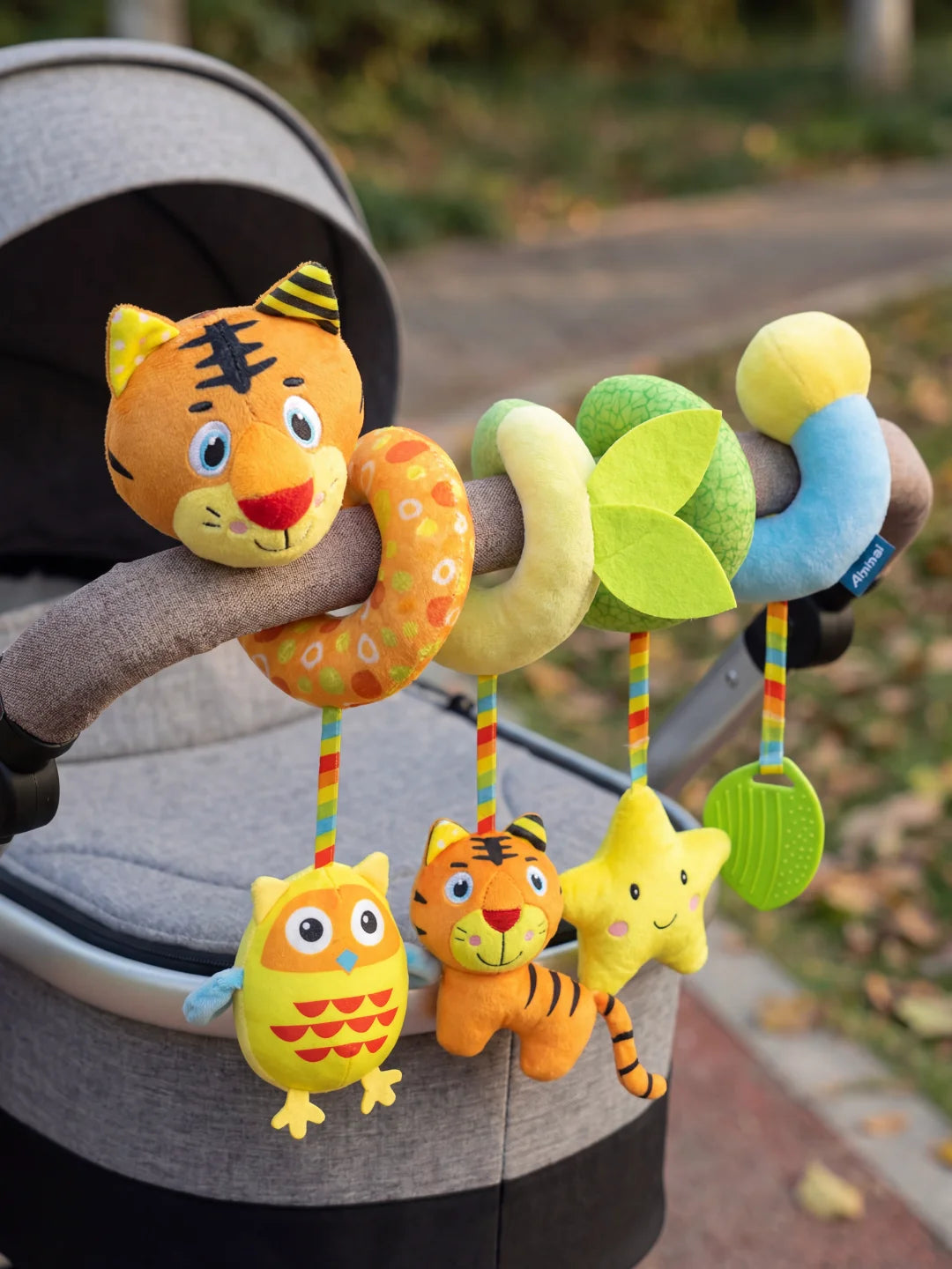 Spirale d'éveil tigre et ses hochets colorés solidement fixés sur une barre de poussette.