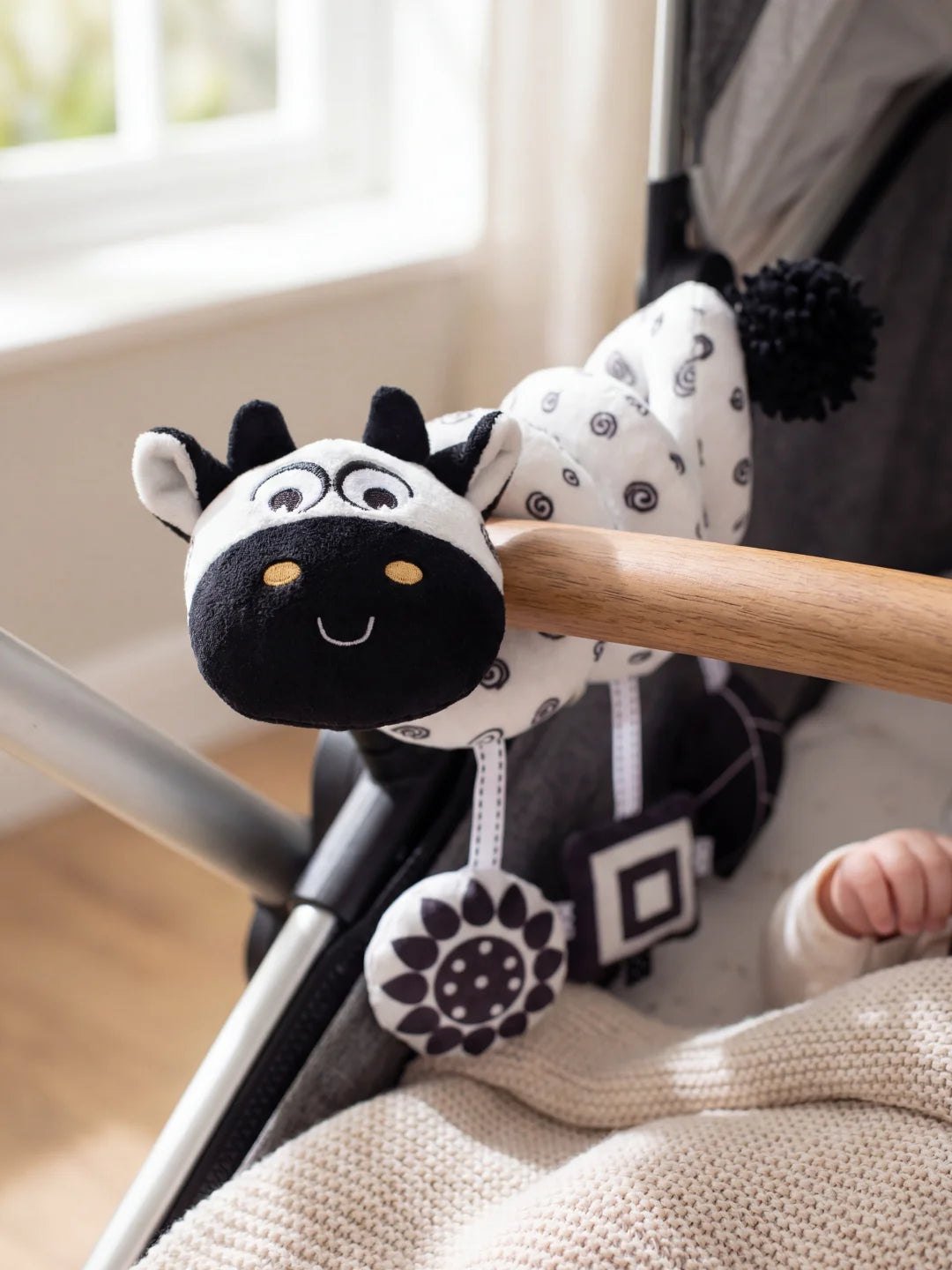 Spirale d'activité vachette installée sur l'arche d'une poussette pour les sorties avec bébé.