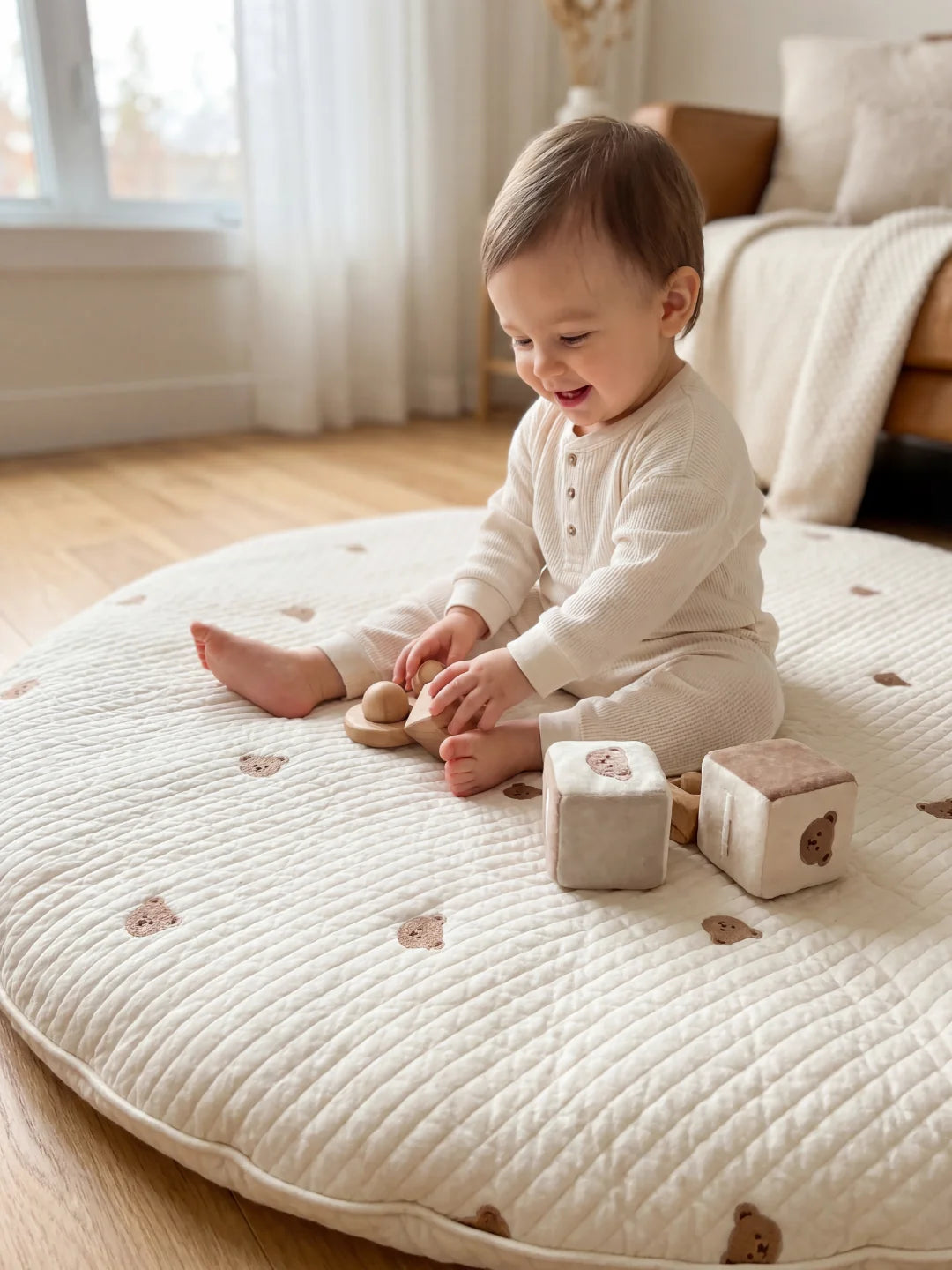 Bébé souriant assis sur un tapis rembourré de haute qualité, manipulant des cubes de jeu en tissu et en bois.