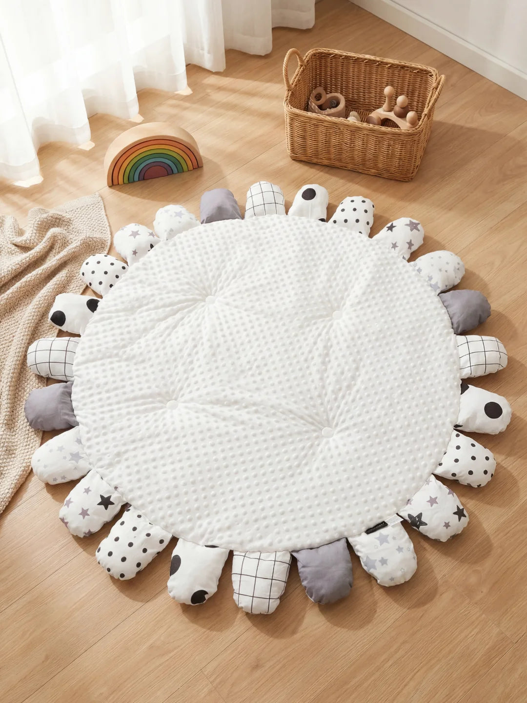 Tapis d'éveil rond blanc minky avec pétales décoratifs aux motifs d'étoiles et de carreaux dans un salon scandinave.