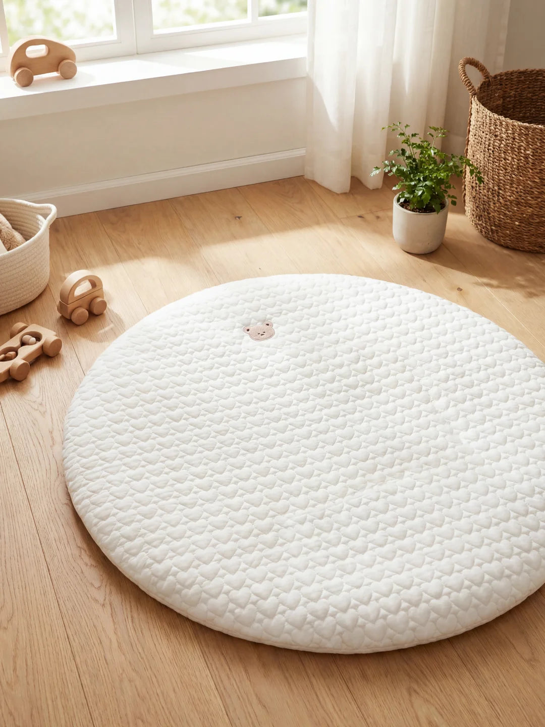 Vue de dessus d'un tapis de sol pour bébé blanc matelassé avec un petit ours brodé au centre, ambiance lumineuse.