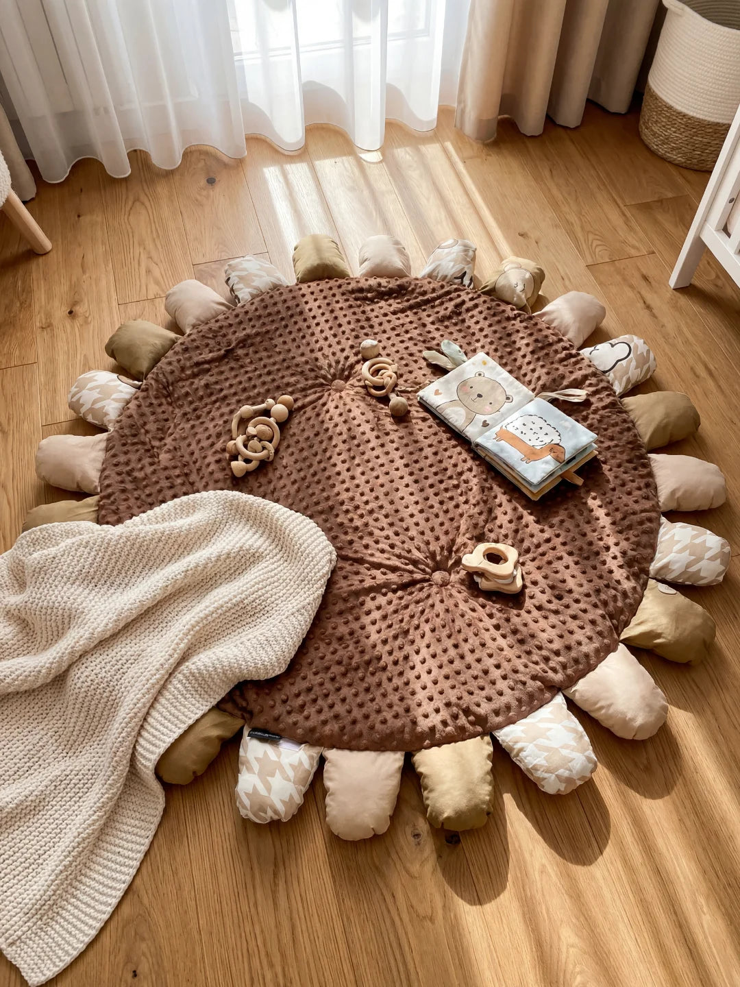 Vue de dessus d'un tapis de sol pour bébé marron avec des jouets d'éveil en bois et un livre en tissu posés sur la texture à picots.