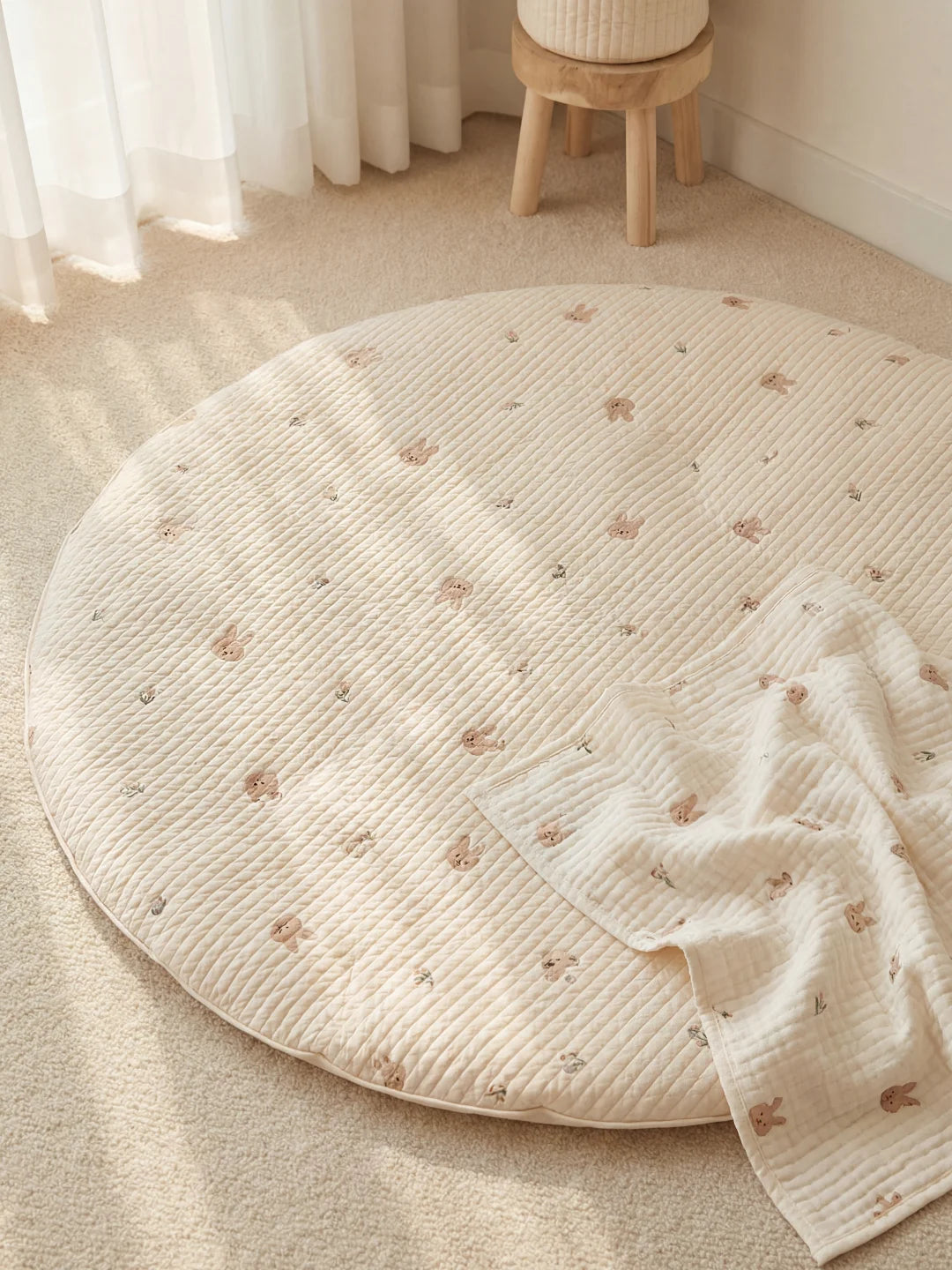 Tapis de sol matelassé pour bébé avec imprimés lapins et couverture en mousseline assortie dans un intérieur doux.