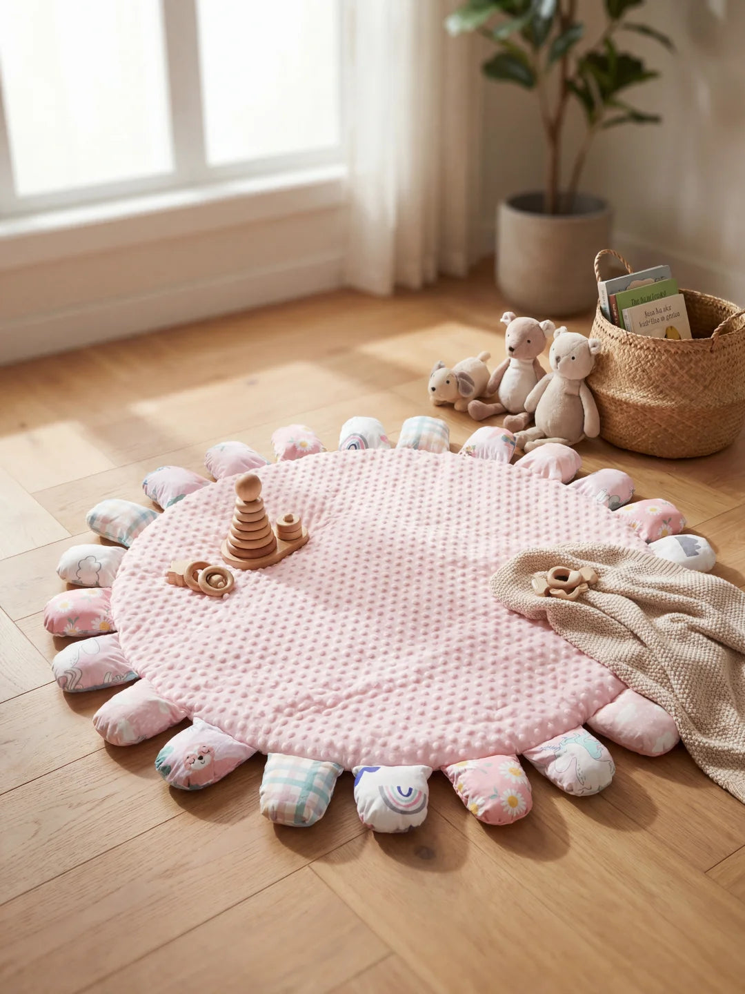 Tapis de sol pour bébé rose à picots sensoriels entouré de pétales rembourrés, posé sur un parquet avec des jouets en bois.