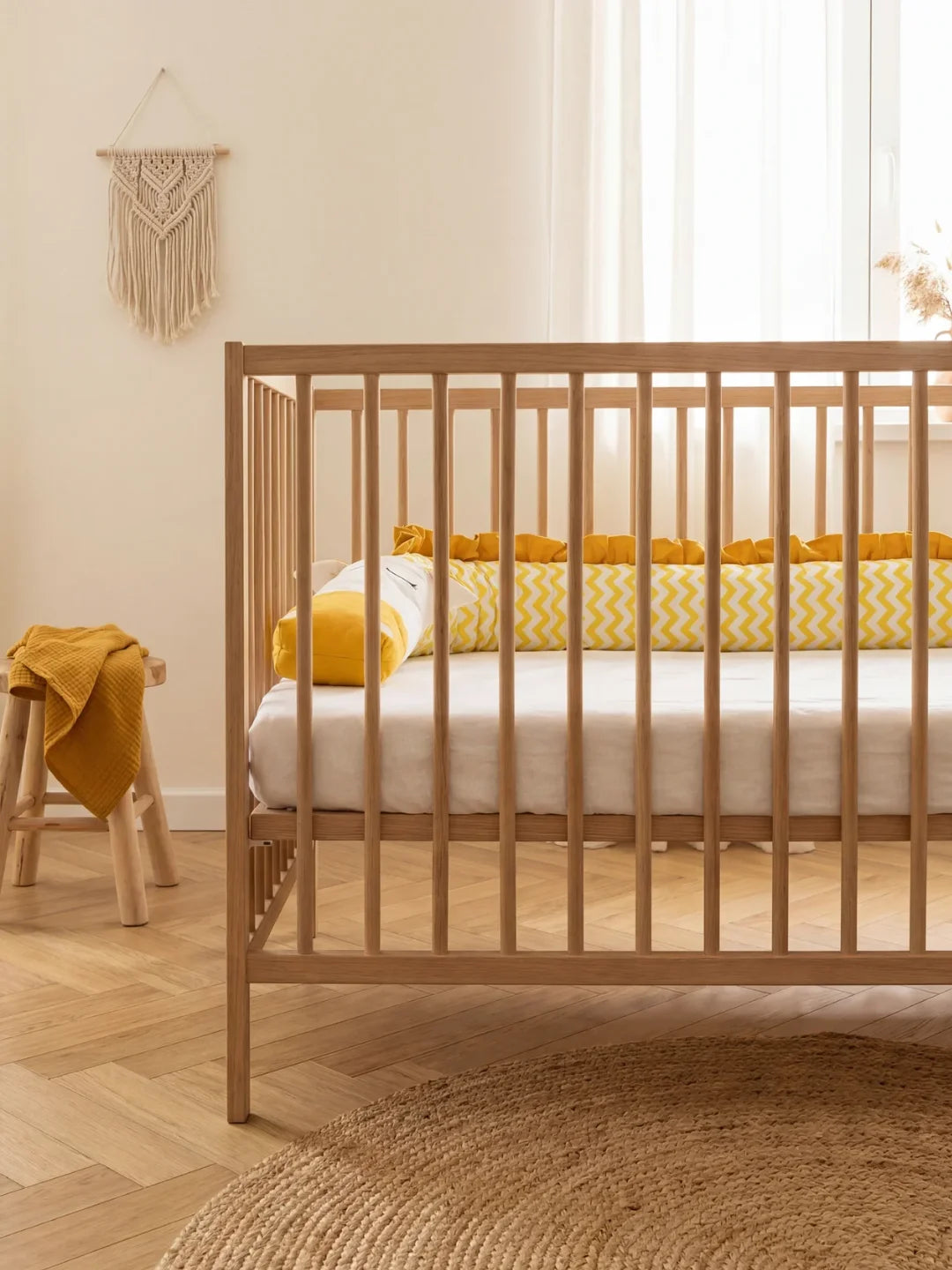 Tour de lit traversin bébé chevron jaune installé dans lit en bois naturel