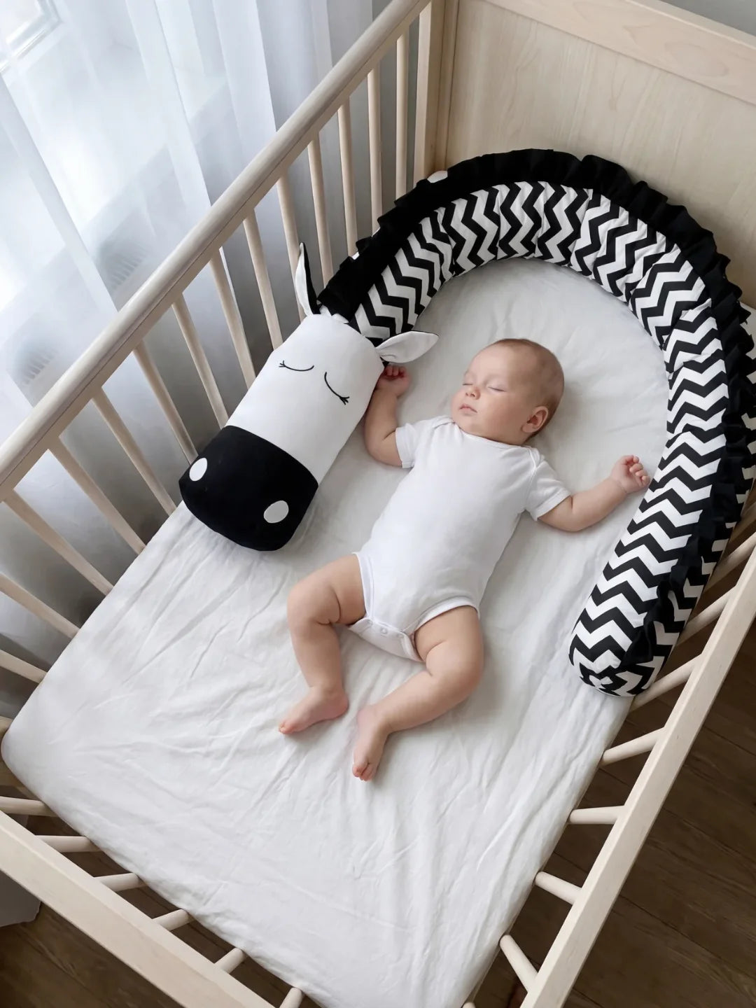 Bébé endormi dans lit avec tour de lit traversin chevron noir et blanc