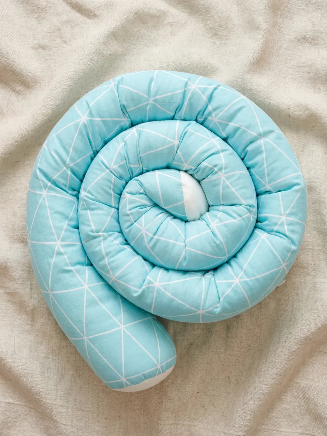 Tour de lit traversin géométrique bleu ciel enroulé en spirale sur drap