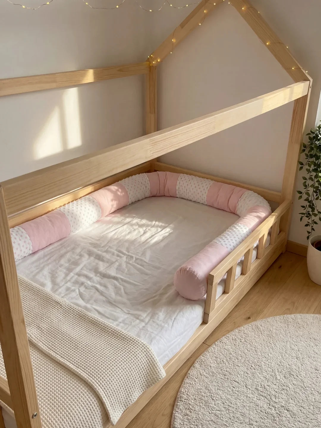 Tour de lit traversin velours rose installé dans lit cabane Montessori en bois