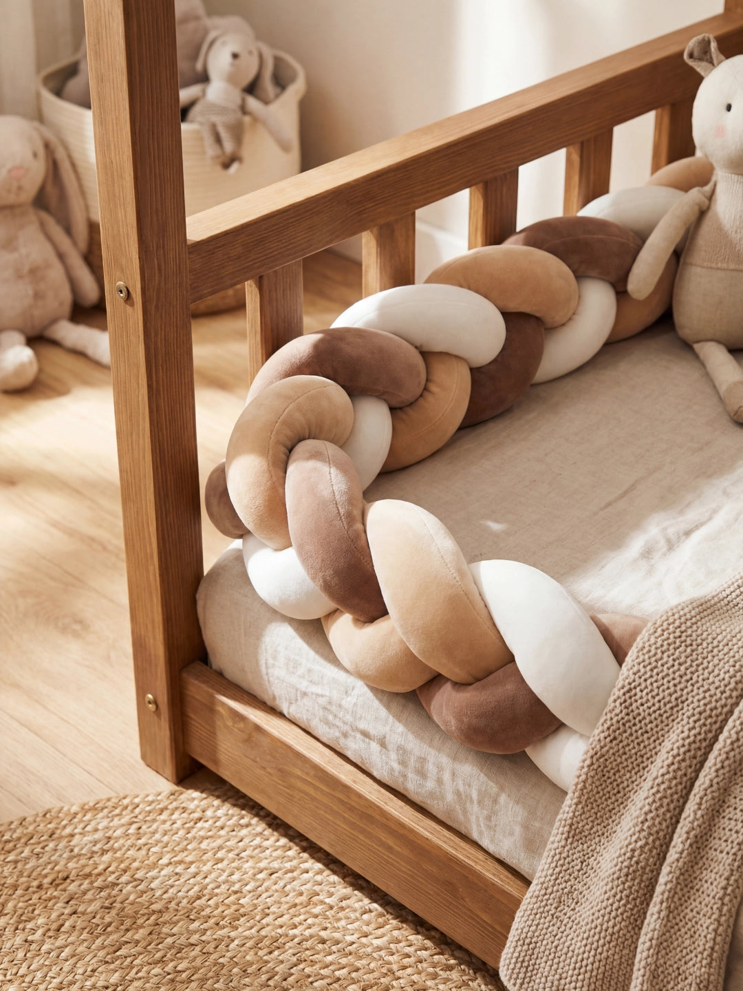 Détail de la texture douce en velours d'un tour de lit tressé aux nuances café et crème, avec une couverture en maille.