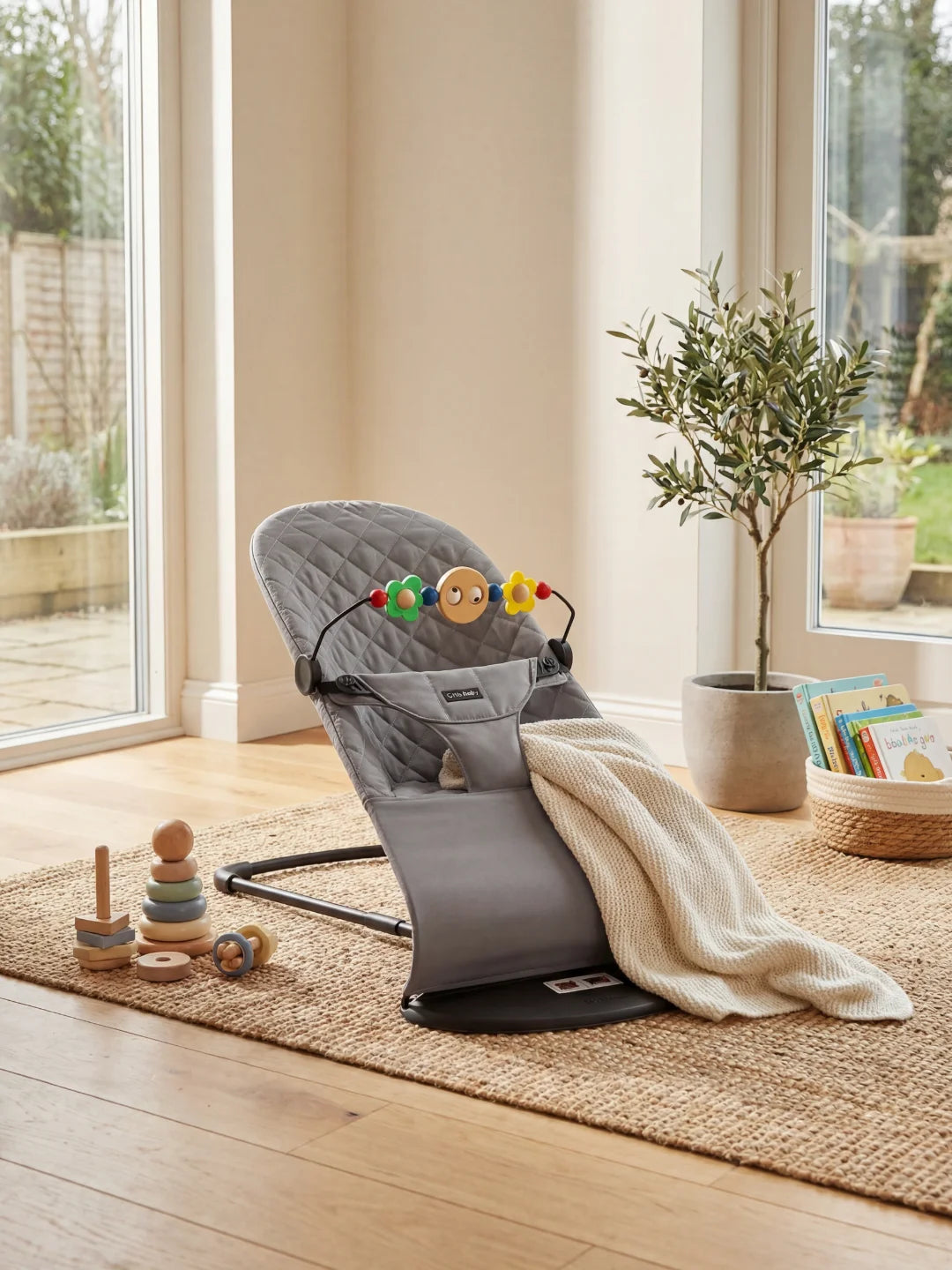 ransat ergonomique gris anthracite avec une arche de jeux en bois installé sur un tapis de salon.