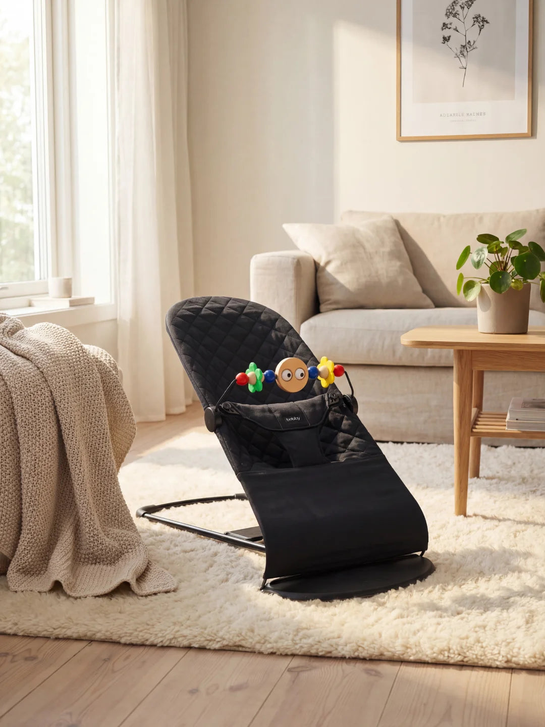 Transat pour bébé noir matelassé avec une arche de jeux colorée, installé dans un salon moderne et chaleureux.