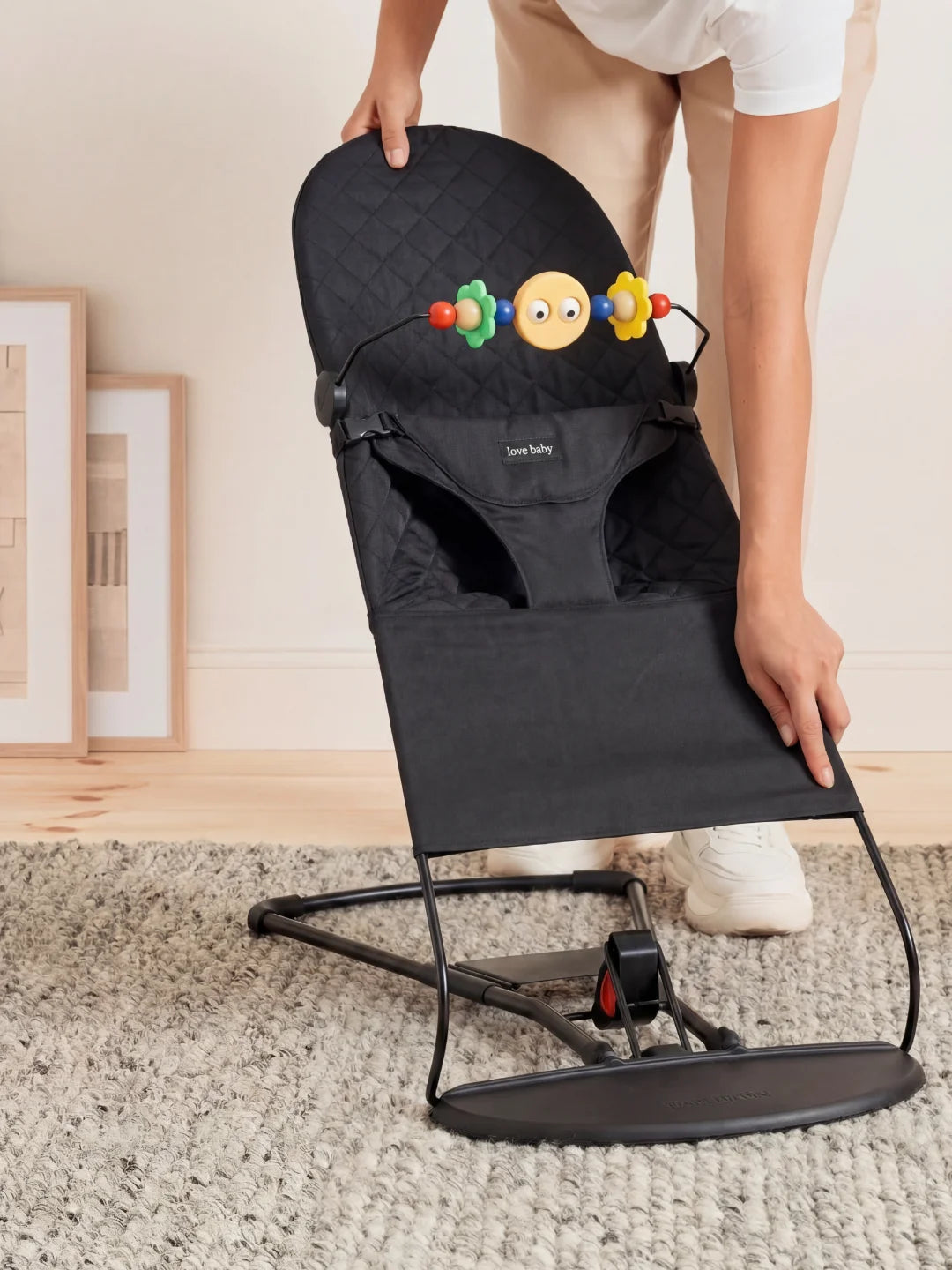 Parent repliant le transat noir compact pour montrer la facilité de rangement et de transport.