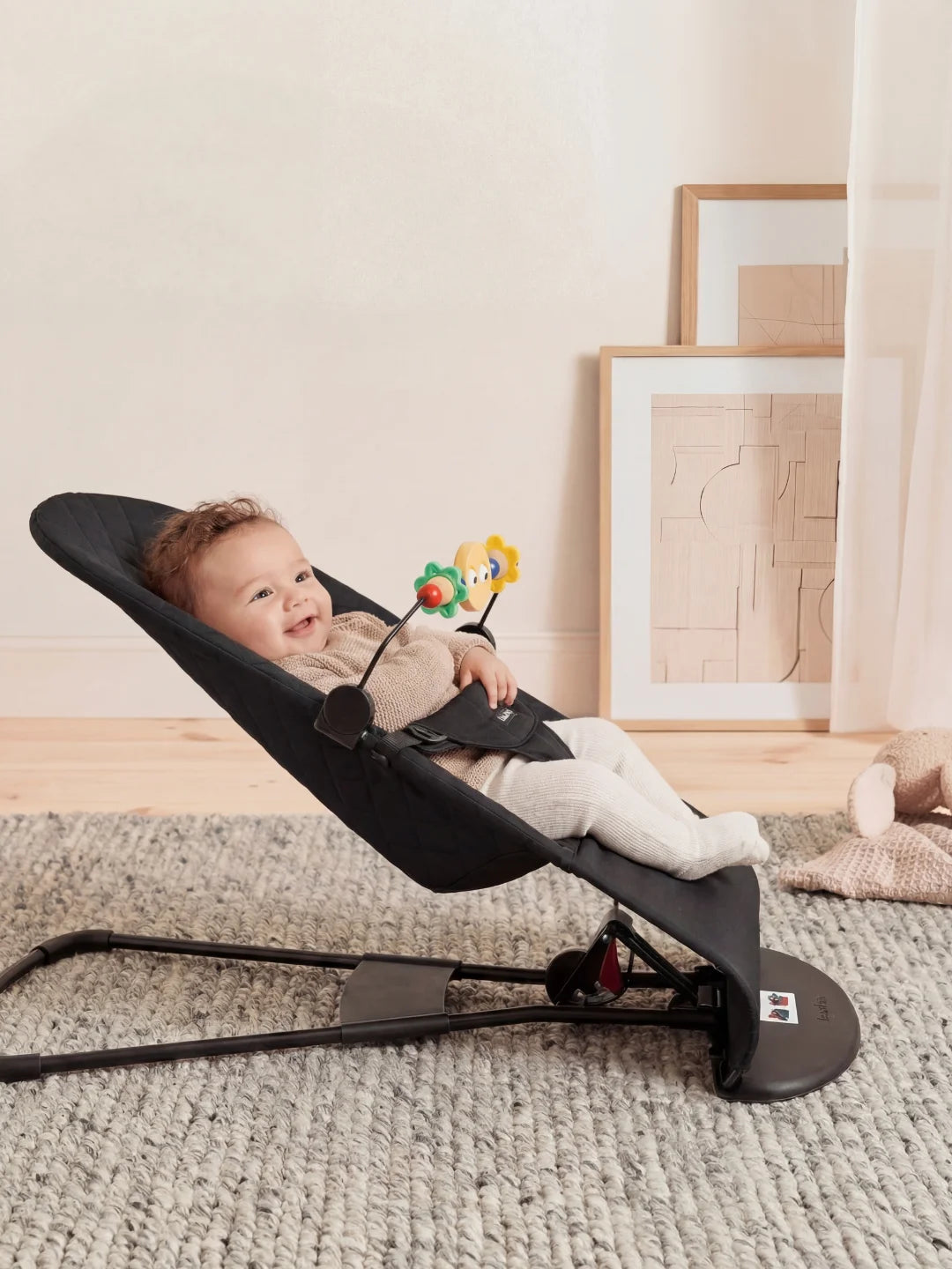 Vue de profil d'un bébé installé confortablement dans un transat noir incliné, favorisant un bon maintien du dos.