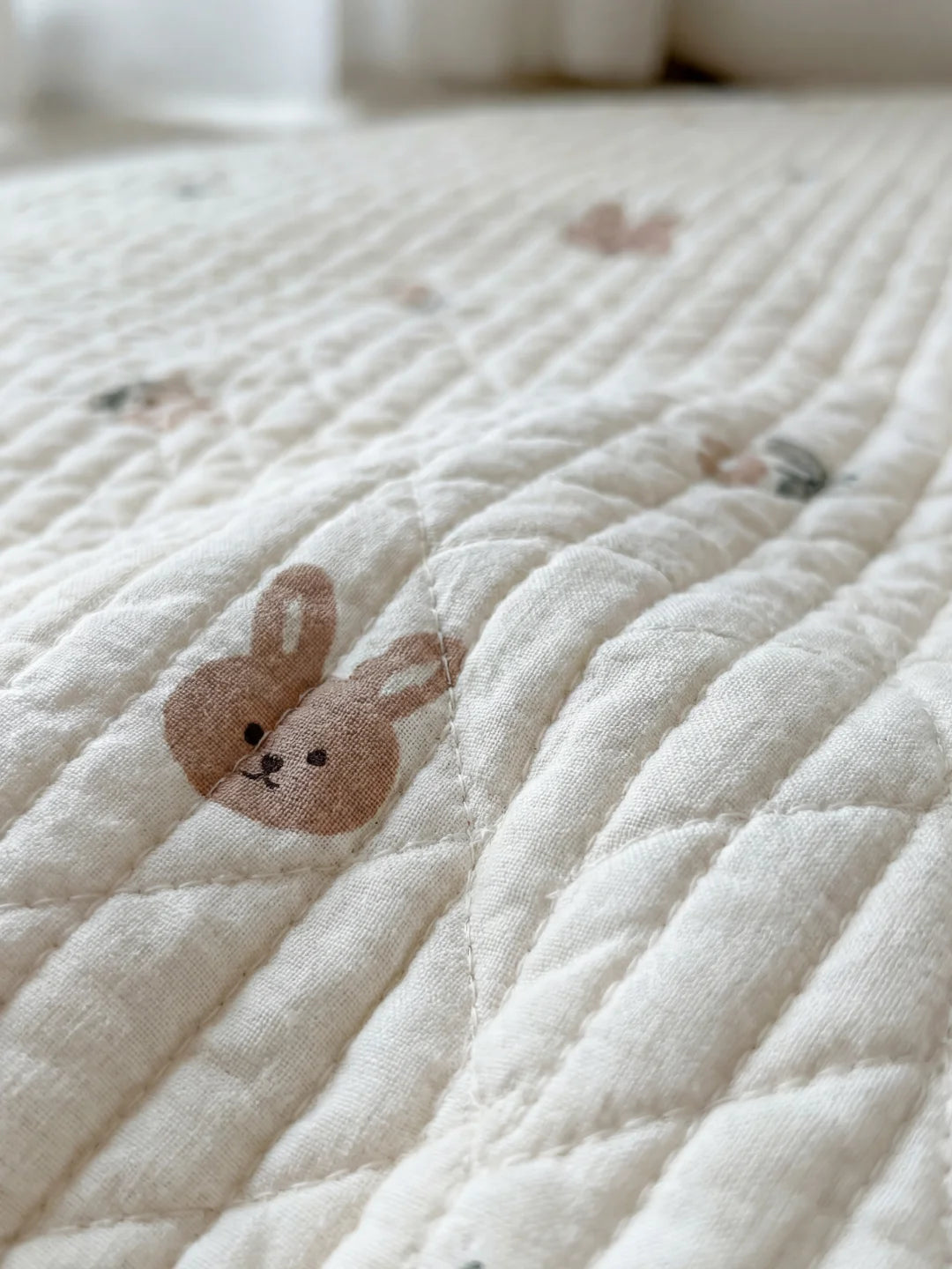 Détail d'une broderie délicate de tête de lapin sur un support textile matelassé blanc de haute qualité.