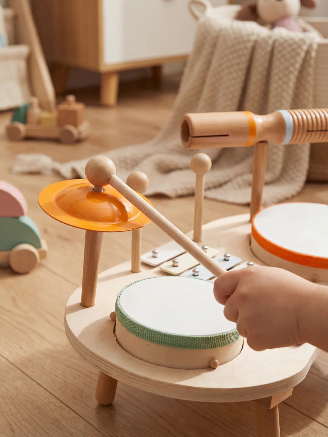 Gros plan sur la cymbale orange et le tambour de la table d'éveil musicale en bois.