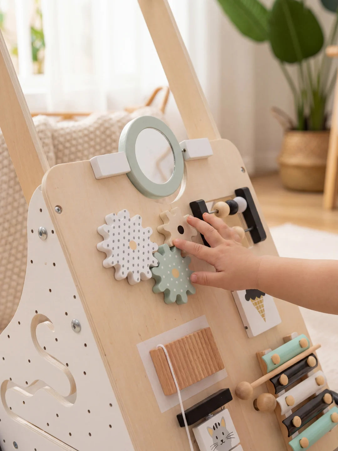 Main d'enfant manipulant les engrenages graphiques à pois du chariot de marche Le P'tit Gourmet.