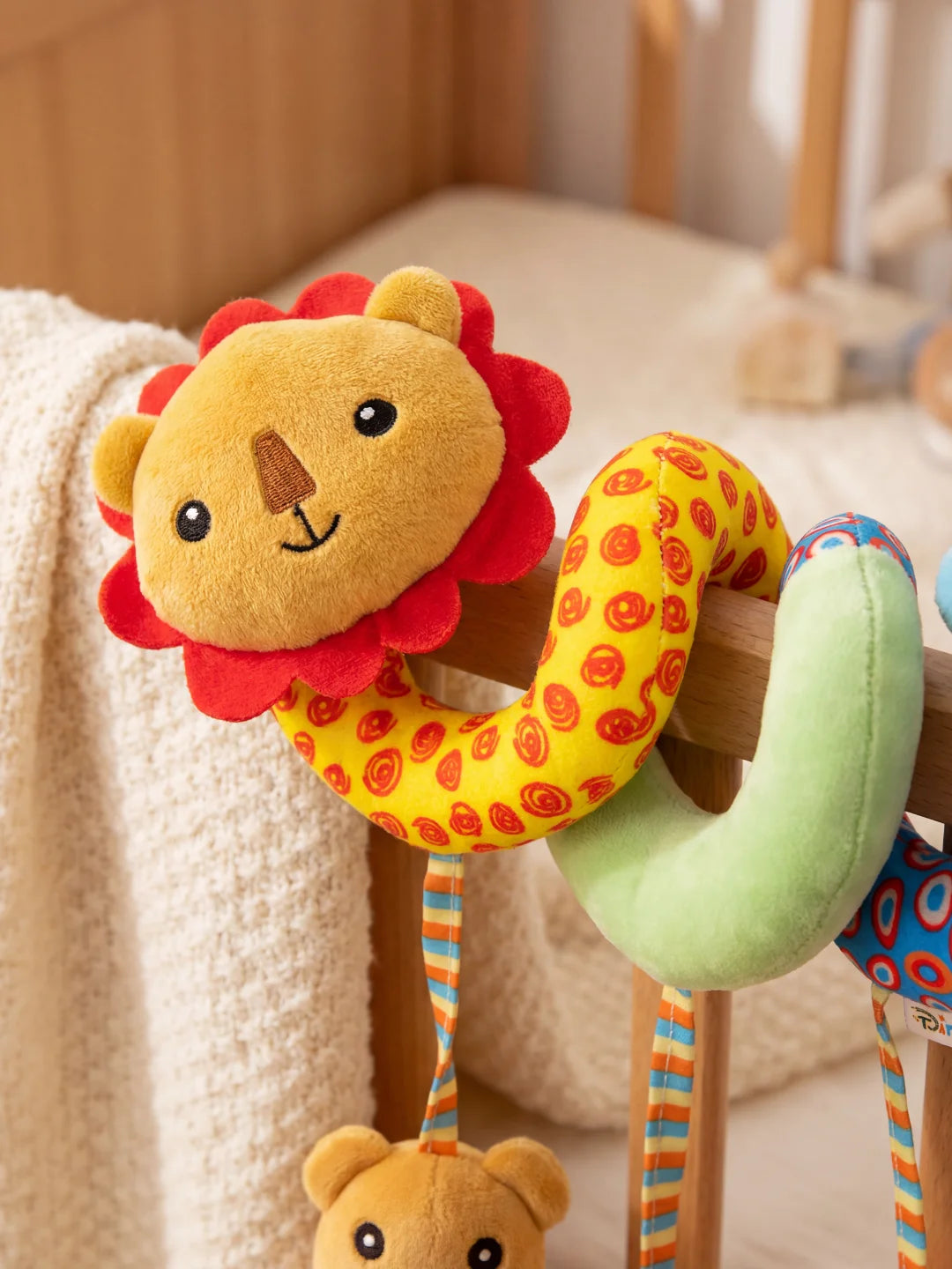 Gros plan sur la tête du lion en peluche jaune avec sa crinière rouge, pièce centrale de la spirale.