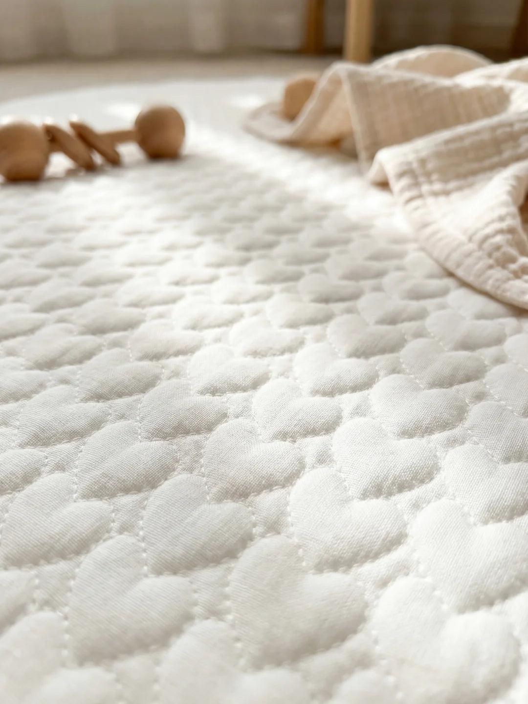 Gros plan sur la texture matelassée en forme de petits cœurs d'un tapis d'éveil haut de gamme pour nouveau-né.