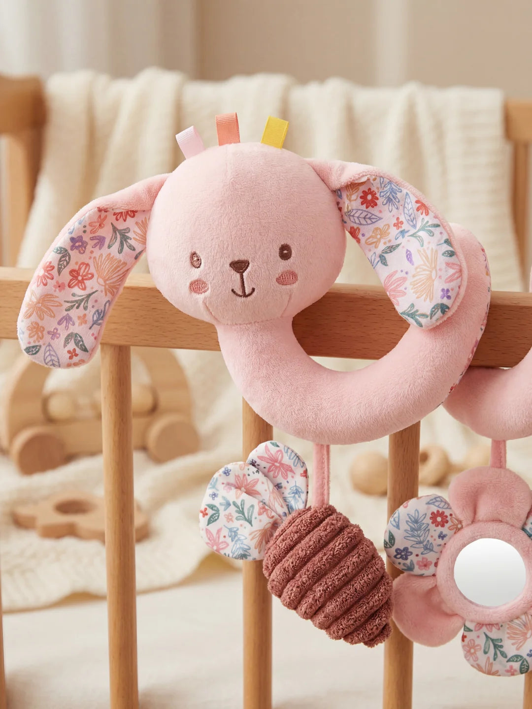 Détail du visage brodé du lapin rose et de ses oreilles aux motifs de fleurs colorées.